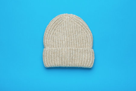 Light knitted hat on a blue background. The concept of hats for cold weather.の写真素材