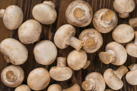 Lots of fresh champignons scattered on a wooden table. Delicious and healthy mushrooms.の写真素材