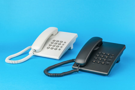 Light and dark telephones on a blue background. The concept of telephone communication. flat lay.の写真素材