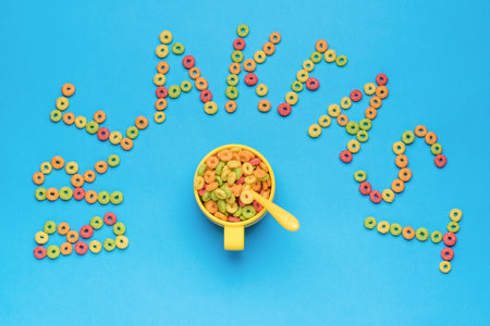 A cup with a spoon and cornflakes and the inscription breakfast on a blue background. The minimum...