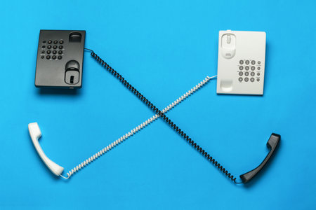 Two phones with their handsets off on a blue background. The concept of telephone communication. flat lay.の写真素材