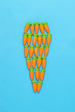 A figurine of a large carrot from many small ones on a blue background. Minimal harvest concept. creative photo. flat lay.の写真素材