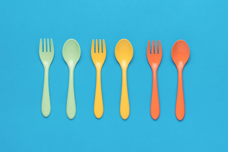 Plastic spoons and forks on a blue background. Minimal concept of plastic tableware. flat lay.の写真素材