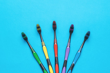 Five multi-colored toothbrushes on a blue background. Minimal oral care concept. flat lay.の写真素材
