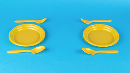 Two yellow cutlery sets on a blue background. Minimal concept of plastic tableware.の写真素材