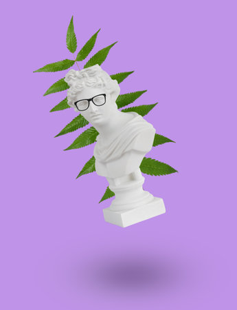 Plaster statuette with glasses on the background of a leaf on a purple background. Collage of contemporary art. minimalism.の写真素材