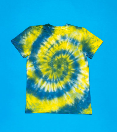 Tie dye style T-shirt in yellow and blue tones on a blue background. The background on the fabric is made with your own hands. flat lay.の写真素材