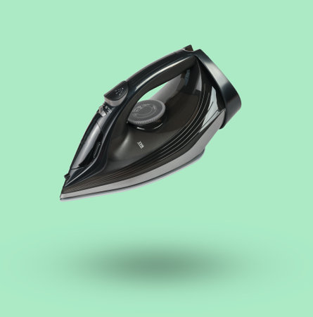 Iron for ironing clothes levitating on a green background. Minimal concept of clothing equipment.の写真素材