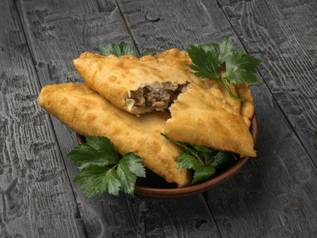 Two fried pies with herbs in a clay bowl on a wooden table. The minimum concept of bakery products with meat.の写真素材