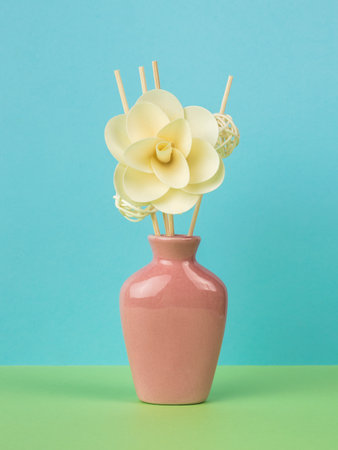 Pink vase for aromatherapy with shelves and a large flower on a green and blue background. The minimal concept of creating fragrances.の写真素材
