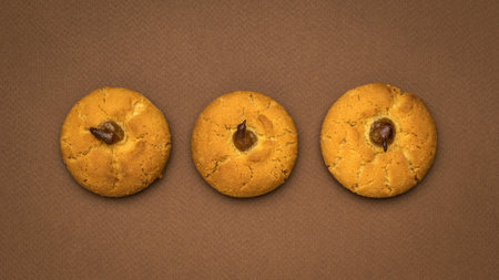 Three fresh round cookies on a brown background. Minimal concept of home baking.の写真素材