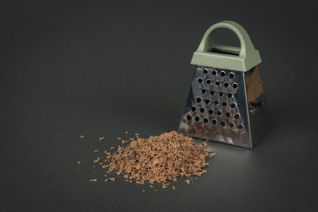 Grated chocolate and a metal grater on a black background. The concept of a popular sweet.の写真素材