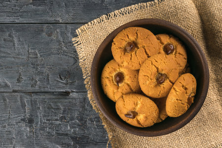 A bowl of cookies on a piece of burlap on a wooden table. Minimal concept of home baking.の写真素材