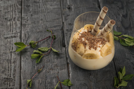 Banana dessert in a glass glass on a wooden table. A delicious and nutritious natural dish.の写真素材