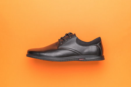 Classic shoes with left foot on orange background. The concept of men's shoes. Flat lay.の写真素材