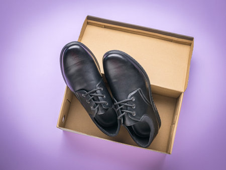 A pair of new men's shoes in a box on a purple background. The concept of men's shoes. Flat lay.の写真素材