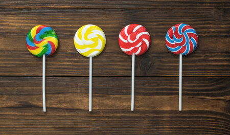 Four lollipops on a stick on a wooden background. The concept of sweets. Flat lay.の写真素材