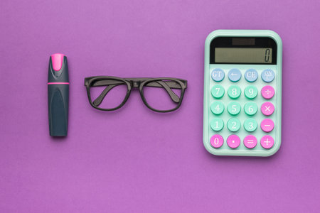Glasses, calculator and marker on a purple background. The concept of financial accounting. Flat lay.の写真素材