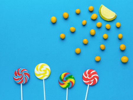 The sun and candy flowers on a blue background. The concept of sweets. Flat lay.の写真素材