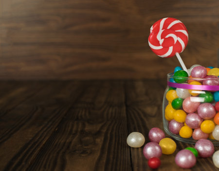 A jar of sweets and a lollipop on a wooden background. A treat for the party.の写真素材