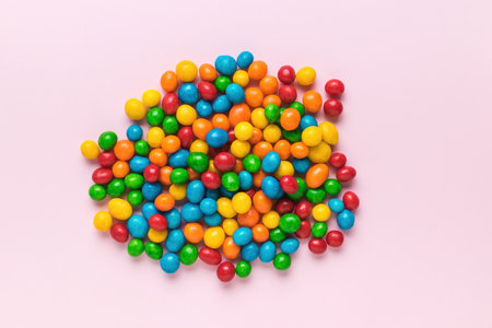 A bunch of colorful candies on a pink background. Candy dragees.