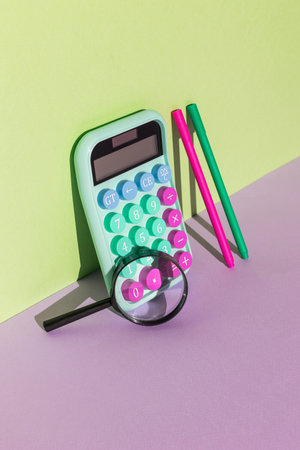 Calculator with pens and magnifying glass on a purple-green background. The concept of financial accounting. Flat lay.の写真素材