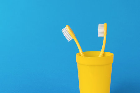 A pair of yellow toothbrushes on a bright blue background. The concept of oral care.の写真素材