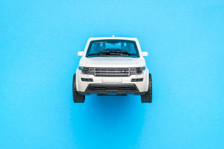 Front view of a white SUV on a blue background. The concept of auto mania. Flat lay.の写真素材