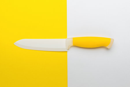 White and yellow kitchen knife on a white and yellow kitchen background. Accessory for cooking. Flat lay.の写真素材