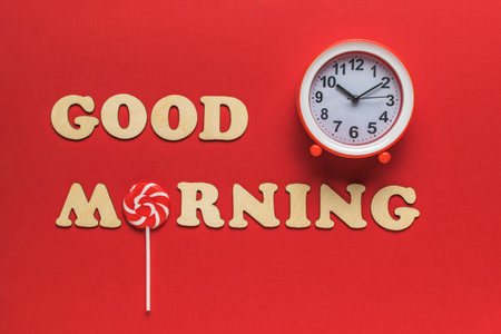 The inscription good morning, clock and lollipop on a red background. Good morning. A good day.