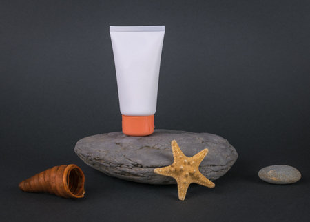 A white tube of cream on a stone pedestal on a dark background. The concept of presenting cosmetics.の写真素材