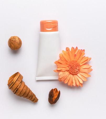 A tube of cream, a flower and aromatic elements on a white background. The concept of body care. Flat lay.の写真素材