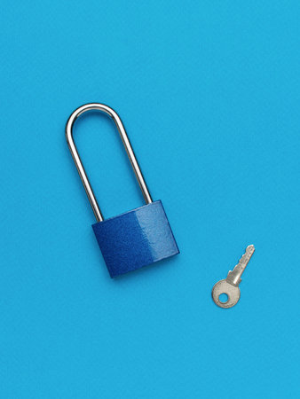 Blue metal lock with a small key on a blue background. The concept of protection.