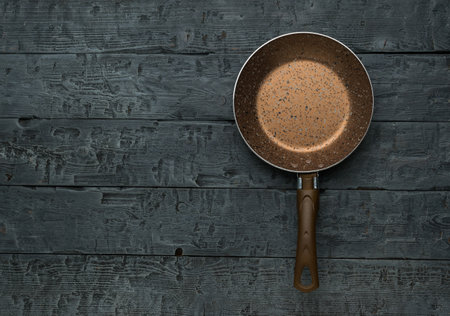 A small brown frying pan on a wooden background. The concept of kitchen accessories.の写真素材