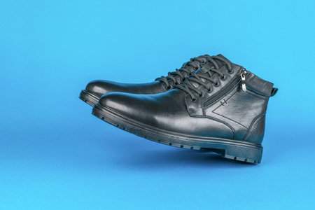 A pair of men's leather shoes levitating on a blue background. The concept of protection from the...