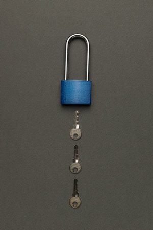 A closed lock with three keys on a gray background. The concept of protection.の写真素材