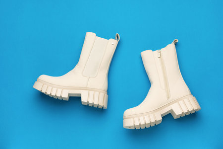 Women's beige leather boots on a light blue background. The concept of shoes for winter.の写真素材