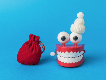 A wind-up toy in a hat and a large bag with gifts on a blue background. The concept of a creative new year.の写真素材