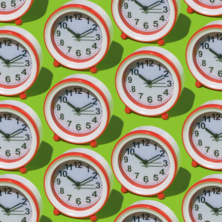 A pattern of a large number of red alarm clocks on a green background. The concept of the passage of time.の写真素材