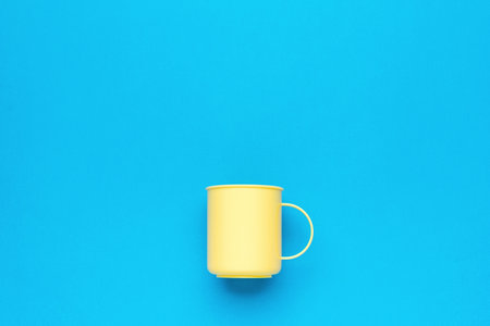 Light yellow mug on a blue background. A vessel for drinks.の写真素材
