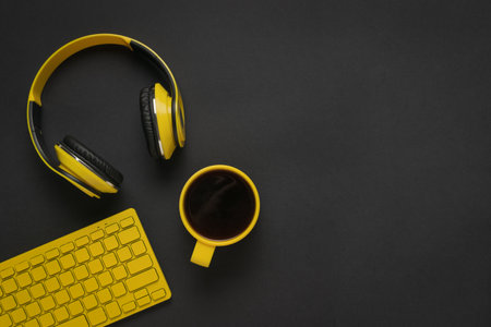 Yellow headphones, coffee and keyboard on a black background. Space for text. The concept of a stylish workplace.の写真素材