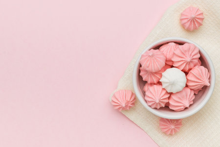 Top view of a bowl with meringue on a fabric on a pink background. Space for text. A sweet dish.の写真素材