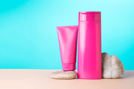 Two bright bottles of crimson color on a beige table on a turquoise background. Presentation of cosmetics.の写真素材