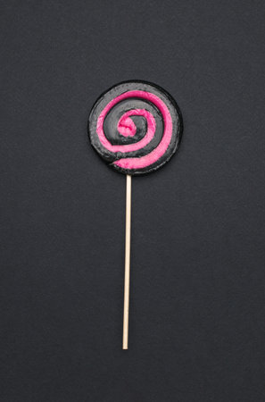 A red and black lollipop on a black background. The concept of sweets. Flat lay.の写真素材