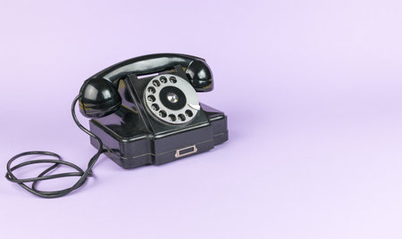 Vintage classic black telephone on a lilac background. The old technique.の写真素材
