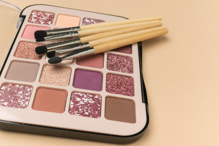 Stylish eye shadow and a set of makeup brushes on a beige background. Women's cosmetics.の写真素材