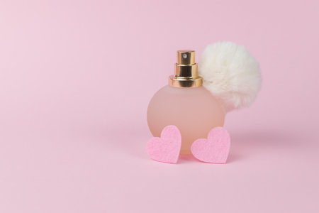 Women's perfume in an original bottle and two pink hearts on a pink background. Women's perfumes.の写真素材
