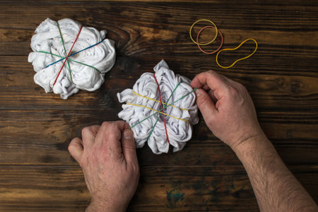 A man prepares T-shirts for coloring in tie dye style. Making clothes at home.