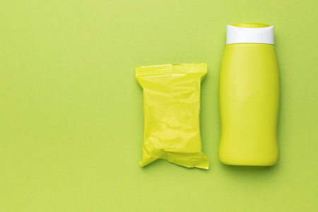 A green shampoo bottle and a green soap package on a green background. Personal hygiene products.