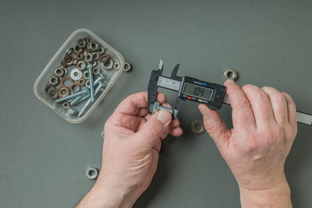 A man measures a metal bolt with an electronic caliper. A tool for accurate measurement of...